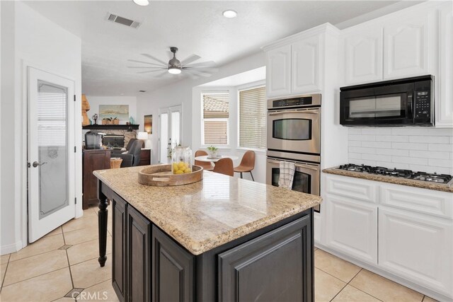 kitchen featuring a center island, light stone countertops, ceiling fan, appliances with stainless steel finishes, and white cabinets