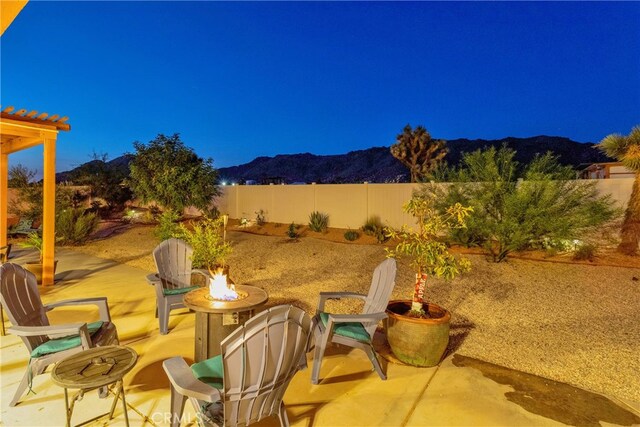 patio at twilight featuring a mountain view and an outdoor fire pit