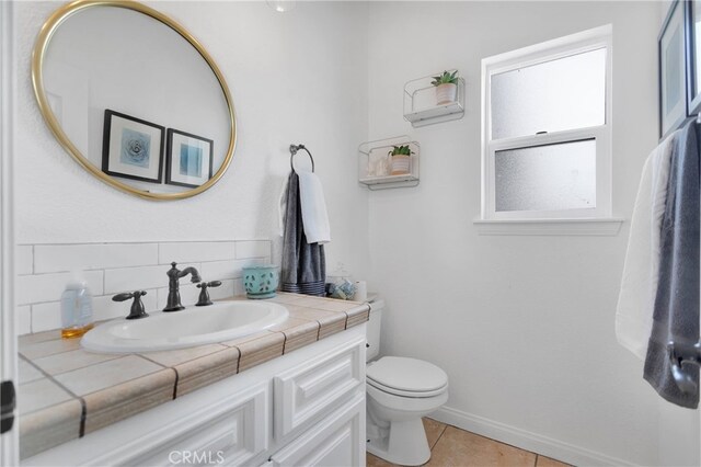 bathroom featuring vanity, toilet, tile patterned floors, and tasteful backsplash