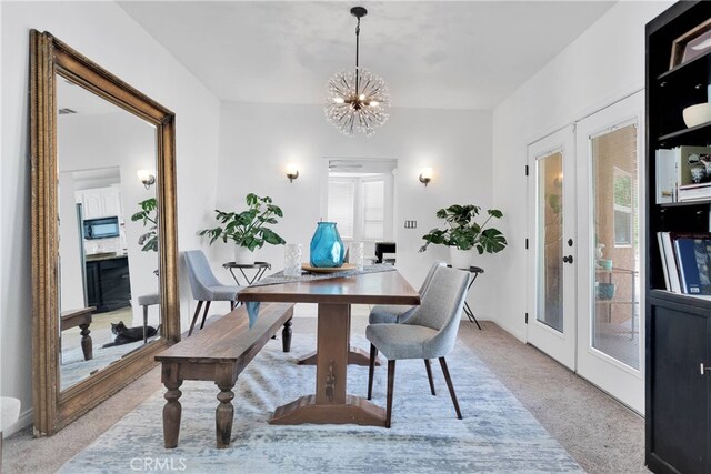 dining area with a notable chandelier, light carpet, and french doors