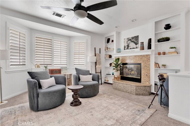 carpeted living room with a high end fireplace, built in features, and ceiling fan