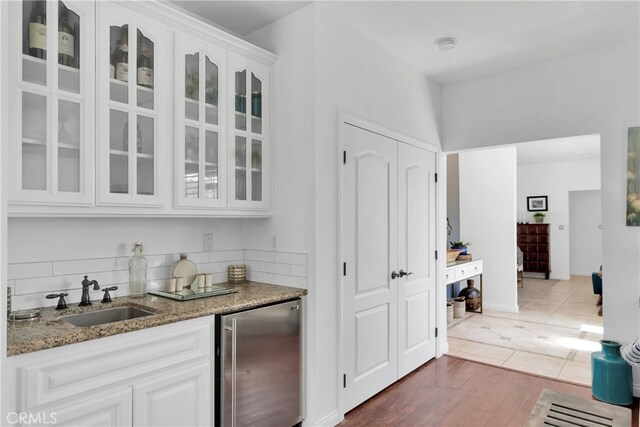 bar featuring dark wood-type flooring, sink, light stone countertops, and white cabinetry