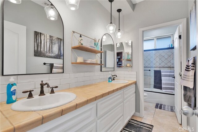 full bathroom featuring vanity, backsplash, tile patterned flooring, toilet, and bathtub / shower combination