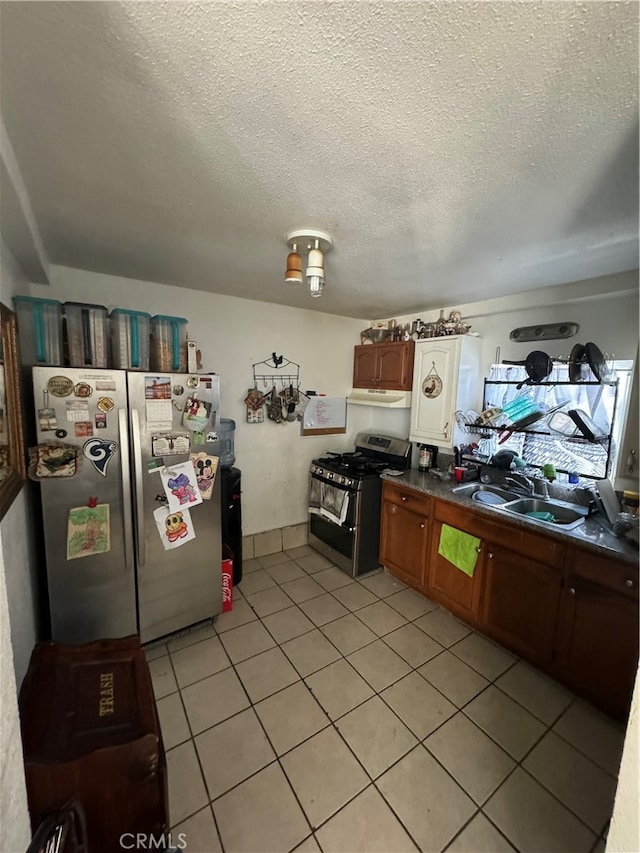 kitchen with light tile patterned flooring, sink, appliances with stainless steel finishes, and a textured ceiling