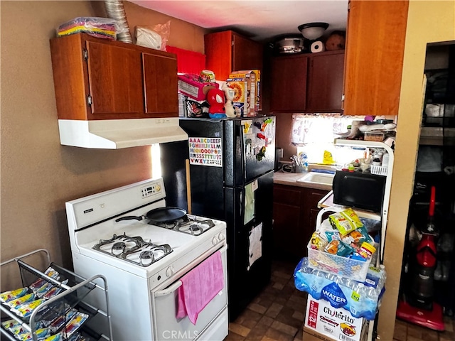 kitchen featuring black fridge, dark tile patterned flooring, white range with gas stovetop, and extractor fan