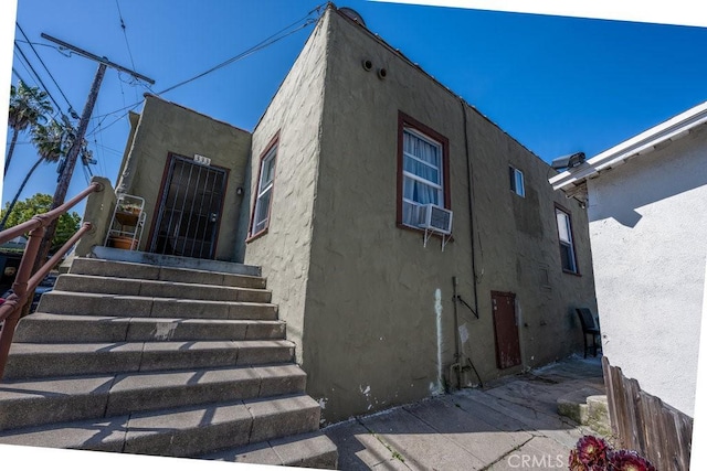 exterior space with stucco siding and cooling unit