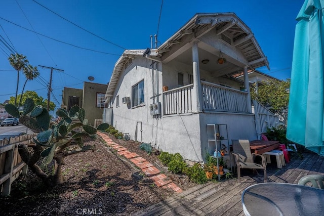 view of side of home with a wooden deck and stucco siding