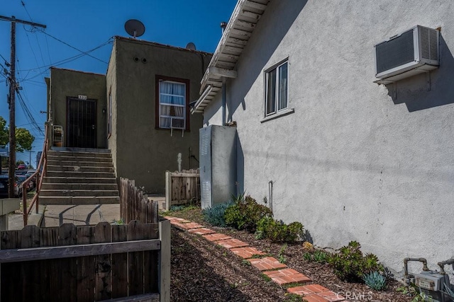 view of property exterior with stucco siding and fence
