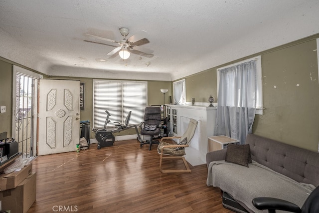 living area with a textured ceiling, wood-type flooring, and ceiling fan