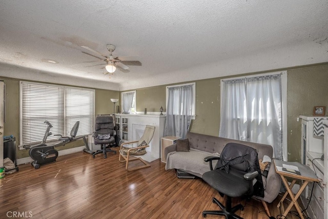 living room with a textured ceiling, ceiling fan, and wood finished floors