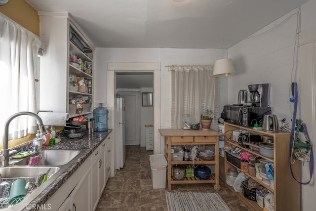 kitchen featuring dark stone counters, white fridge, dark tile patterned floors, white cabinets, and sink