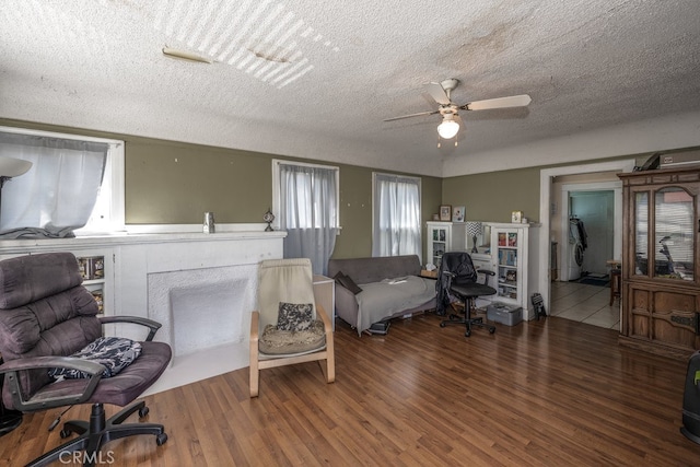 interior space featuring hardwood / wood-style flooring, a textured ceiling, a fireplace, and ceiling fan