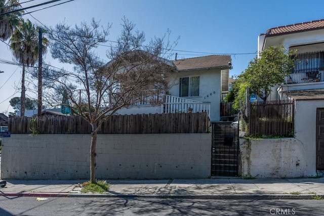 bungalow featuring stairway, a fenced front yard, and stucco siding