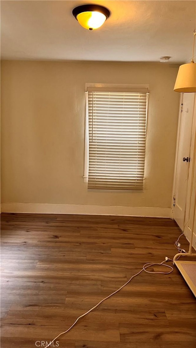 unfurnished room with baseboards and wood finished floors