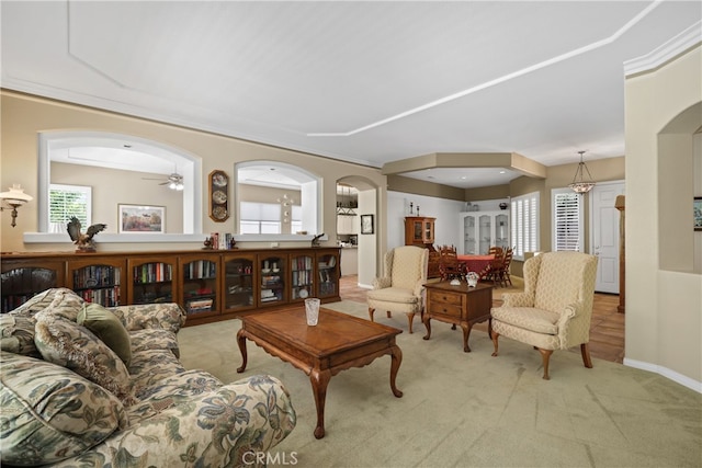 living room featuring ceiling fan, light carpet, and ornamental molding