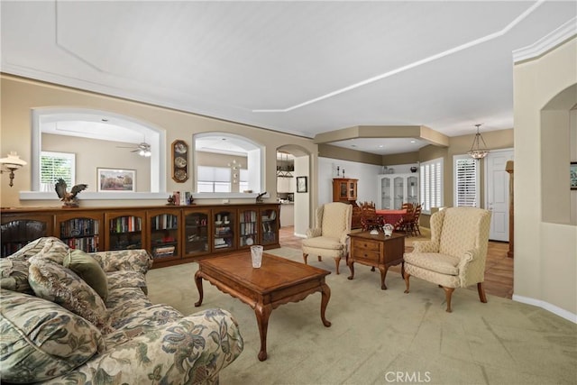 living room with arched walkways, baseboards, and light colored carpet