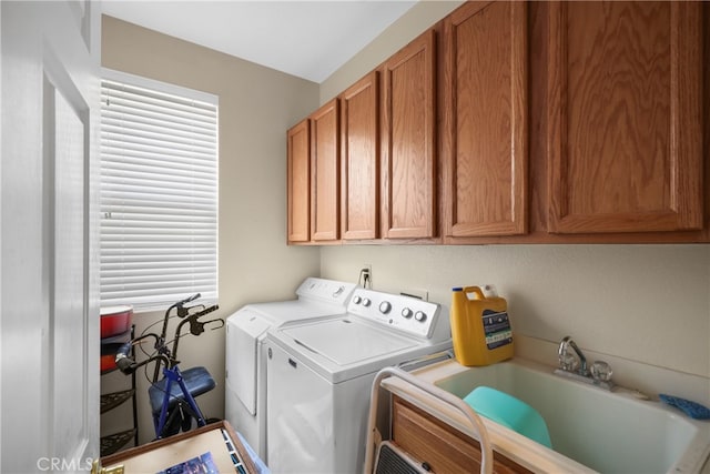 clothes washing area featuring sink, washer and dryer, and cabinets