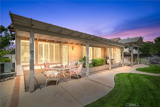 back house at dusk with a pergola, a yard, and a patio area