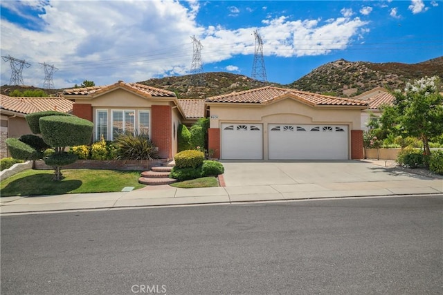 view of front of property featuring a garage, concrete driveway, a mountain view, and stucco siding