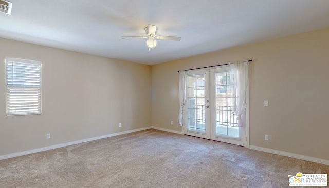 carpeted spare room with ceiling fan and french doors