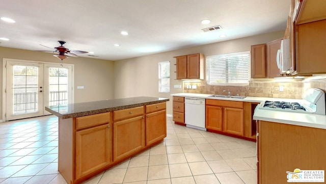 kitchen with a kitchen island, white appliances, backsplash, sink, and ceiling fan