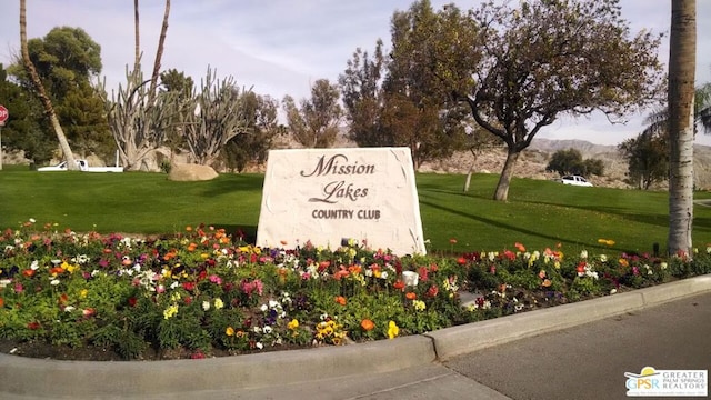 community / neighborhood sign with a lawn and a mountain view