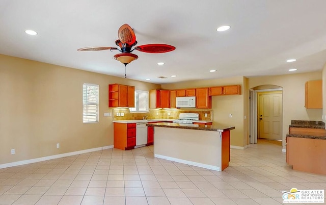 kitchen with white appliances, light tile patterned floors, a center island, decorative backsplash, and ceiling fan