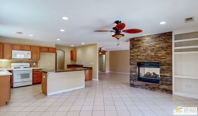 kitchen featuring white appliances, a fireplace, light tile patterned floors, a center island, and ceiling fan