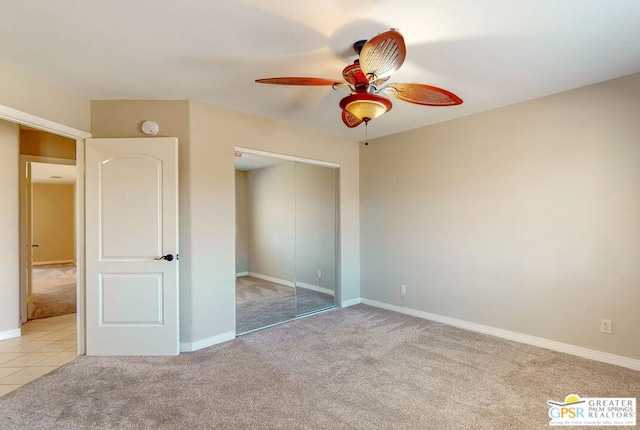 unfurnished bedroom featuring light carpet, ceiling fan, and a closet