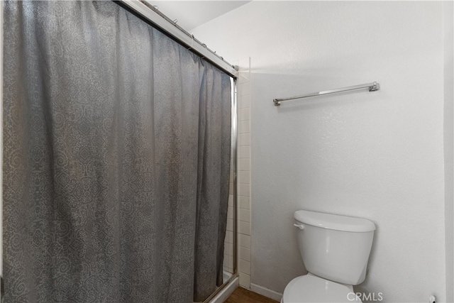 bathroom featuring toilet and a shower with shower door