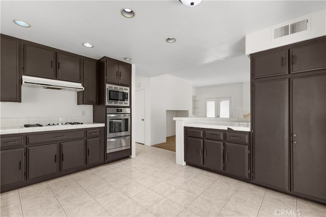 kitchen featuring dark brown cabinets, light tile patterned floors, appliances with stainless steel finishes, and extractor fan