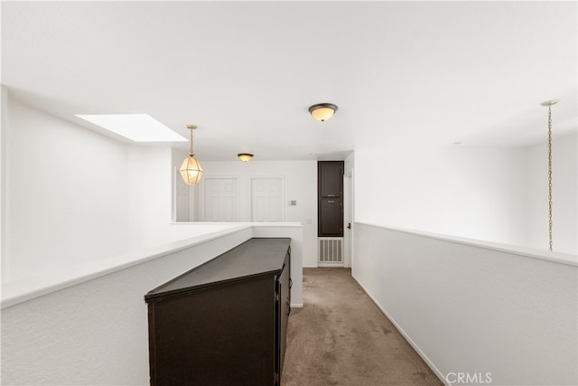 hall with a skylight and light colored carpet