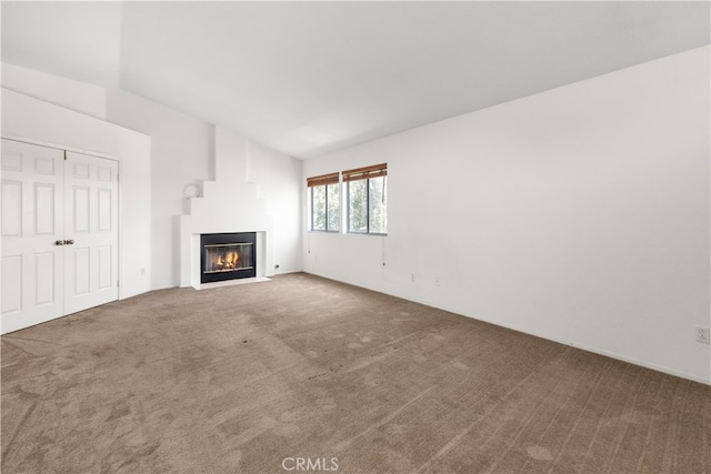 unfurnished living room featuring vaulted ceiling and carpet