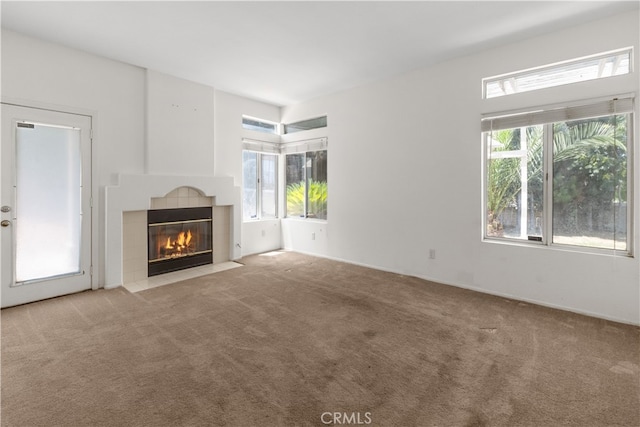 unfurnished living room featuring a tiled fireplace and light carpet