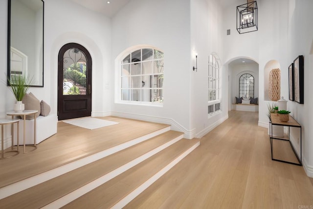 entryway with light hardwood / wood-style floors, a chandelier, and a high ceiling