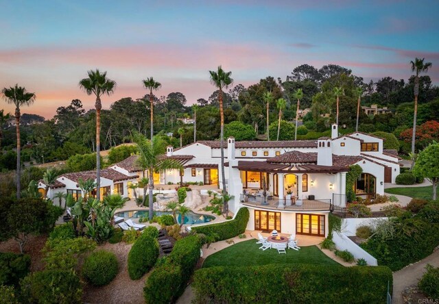 back house at dusk with a patio area and a yard