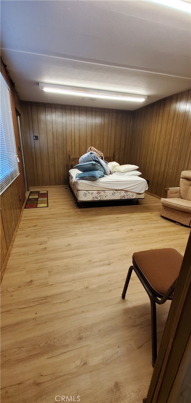 bedroom featuring light wood-type flooring and wood walls