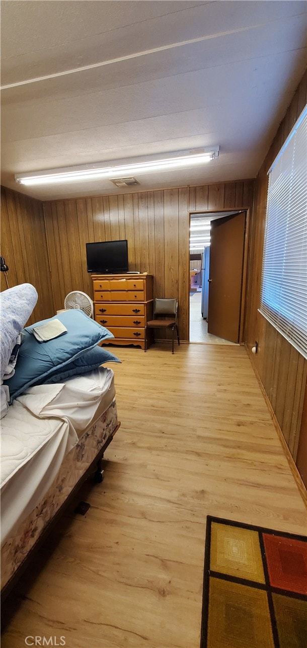 bedroom featuring light wood-type flooring and wood walls