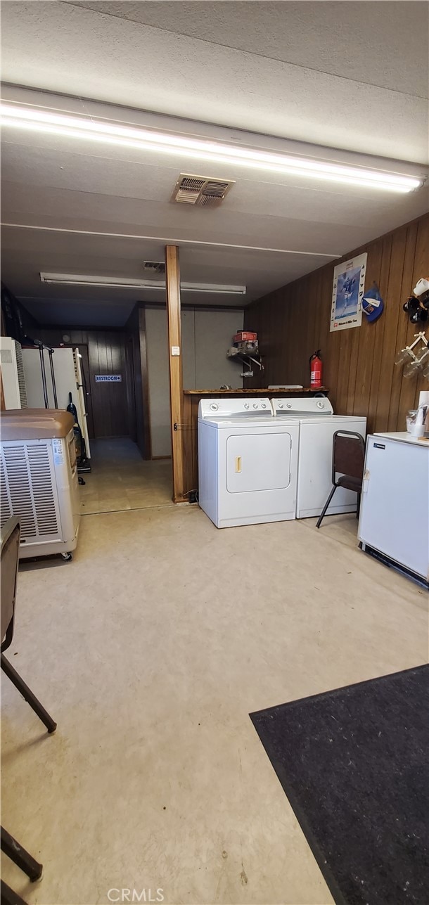 clothes washing area featuring wooden walls and separate washer and dryer