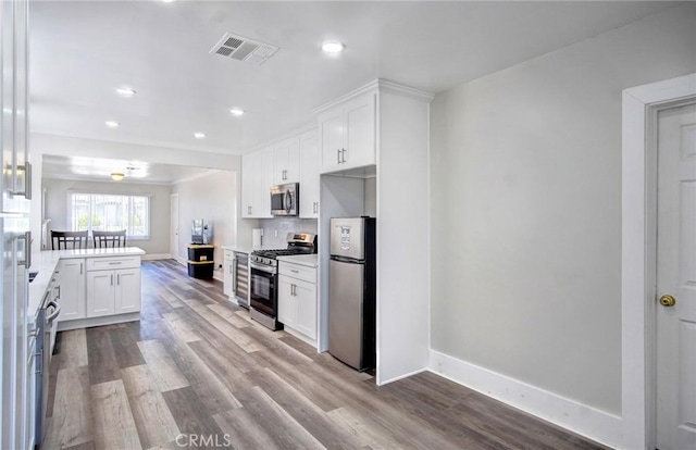 kitchen featuring visible vents, white cabinets, a peninsula, stainless steel appliances, and light countertops