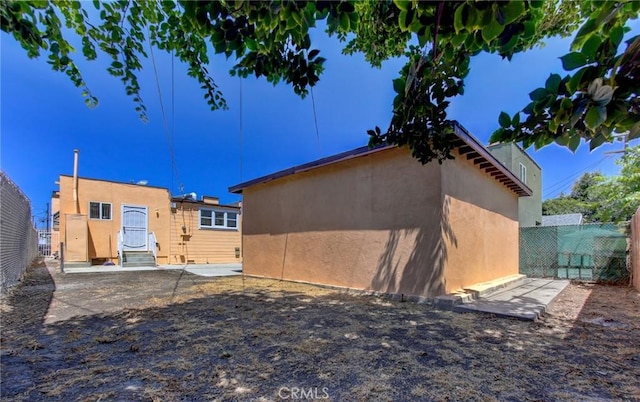 rear view of property with fence, a patio, and stucco siding