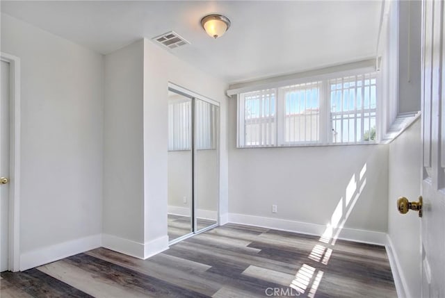 bedroom featuring a closet, dark wood-style flooring, visible vents, and baseboards