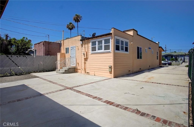 rear view of property with crawl space, fence, and concrete driveway