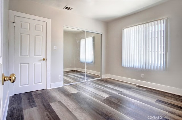 unfurnished bedroom with a closet, multiple windows, and hardwood / wood-style floors