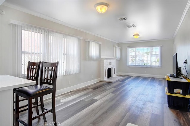 living room with baseboards, visible vents, crown molding, and wood finished floors