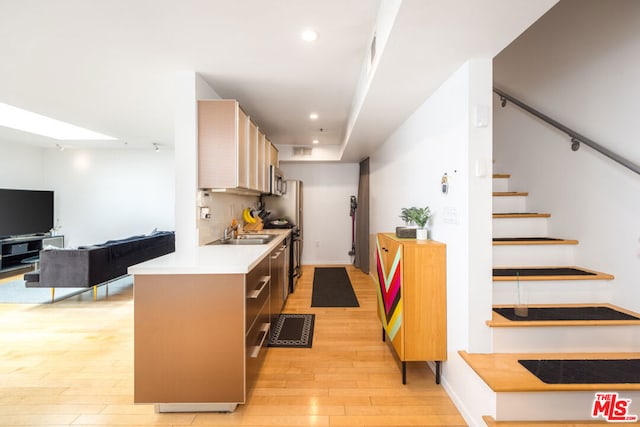 kitchen with light wood-type flooring, a skylight, and sink