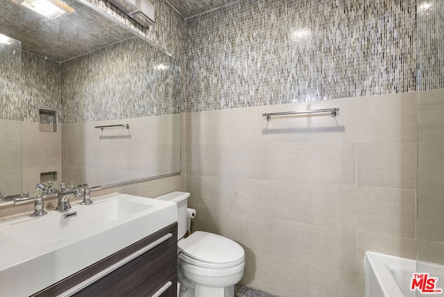 bathroom featuring vanity, toilet, tile walls, and a bathing tub