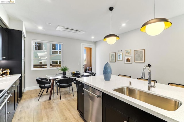 kitchen featuring pendant lighting, dishwasher, sink, and light wood-type flooring