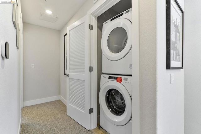 clothes washing area with stacked washing maching and dryer