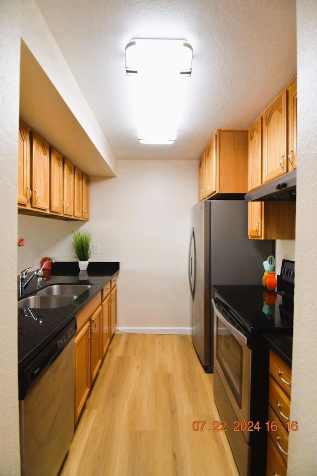 kitchen featuring sink, light hardwood / wood-style flooring, a textured ceiling, and appliances with stainless steel finishes